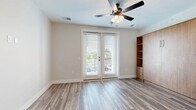 Located at 484 Lazelle Rd in Columbus, Ohio, this efficiently designed studio offers a thoughtful layout that maximizes every square foot. The combined kitchen and living area serves as the heart of the unit, featuring wood-look plank flooring that flows seamlessly throughout the space. The galley-style kitchen is well-appointed with white shaker cabinetry accented by matte black hardware, a tile backsplash, light quartz countertops, and a full suite of stainless steel appliances including a refrigerator, range, built-in microwave, and dishwasher. A built-in counter ledge with open shelving above adds a functional pantry area just off the kitchen. The living area is bright and airy, anchored by a ceiling fan and a set of double glass doors that invite natural light and open to an outdoor balcony with exterior views. The bathroom features a white vanity with quartz countertop, consistent with the unit's clean aesthetic, and wood-look flooring continues throughout. Two closets with wire shelving provide practical storage solutions, while a dedicated laundry space adds everyday convenience. The unit's neutral palette, modern finishes, and efficient use of space make it a well-rounded offering in the Columbus area.