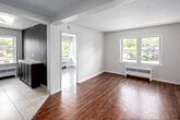 Located at 939E Western Road in London, Ontario, this 2-bedroom, 1-bathroom unit offers a efficiently arranged single-floor layout. Rich hardwood-style flooring runs throughout the main living and bedroom areas, providing a warm, cohesive look across the space.

The primary bedroom is a comfortable size, featuring a sliding-door closet, a window that brings in natural light, and a textured ceiling. A radiator unit provides consistent heating. The second bedroom is a more compact space with clean white walls, hardwood-style flooring, and a window offering outdoor views, making it suitable as a guest room or home office.

The kitchen is well-appointed with dark espresso cabinetry extending to the ceiling for ample storage, stainless steel appliances including a full-size refrigerator, stove, and microwave, complemented by a tile backsplash and light tile flooring. A window above the sink allows natural light to filter in.

The bathroom is clean and functional, featuring light tile flooring, grab bars, a wall-mounted medicine cabinet with mirror, and straightforward fixtures. A hallway connects the rooms, completing the unit's practical layout. Neutral tones and consistent finishes throughout give the space a cohesive, move-in-ready feel.