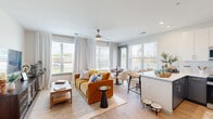 This well-appointed 2-bedroom, 2-bathroom residence in Fredericksburg, VA offers a thoughtfully designed single-floor layout filled with natural light. The welcoming entrance leads down a clean, bright hallway with light wood-style flooring that flows throughout the home. The open-concept living, dining, and kitchen area serves as the heart of the space, featuring large windows with views to the outdoors, a ceiling fan, and a seamless connection between all three zones. The contemporary kitchen stands out with two-tone cabinetry — white uppers and slate-blue lowers — paired with white quartz countertops, a subway tile backsplash, and a full suite of stainless steel appliances including a range, microwave, dishwasher, and refrigerator. A breakfast bar provides additional seating. The primary bedroom is a comfortable retreat with ample space, while the second bedroom features a large window with natural light. Both bathrooms are finished with gray cabinetry, white quartz vanities, and wood-style flooring — one with a soaking tub and the other with a walk-in shower. Five closets provide generous storage throughout. A private balcony completes this modern, move-in-ready home.