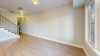 Located at 1265 Birchmount Rd in Toronto's Scarborough district, this contemporary multi-storey townhouse offers a well-organized layout spread across three floors. The main level hosts a spacious open-concept kitchen, dining, and living area, highlighted by a sleek kitchen with white cabinetry, a dark-topped island, subway tile backsplash, stainless steel appliances, and stylish pendant lighting. Light hardwood flooring flows throughout, complementing the bright, neutral palette of the interiors. A clean, tile-floored powder room with a pedestal sink is also conveniently located on this level. The second floor accommodates multiple rooms featuring large windows that invite abundant natural light and offer pleasant outdoor views of the surrounding Toronto neighbourhood. A full bathroom on this floor includes a soaker tub with classic white subway tile surround and chrome fixtures. Connecting all levels is a well-lit staircase with a contemporary wood-and-iron railing. The uppermost level opens to a rooftop terrace via large sliding glass doors, offering expansive city views — a standout feature of this property. Throughout, the space maintains a clean, modern aesthetic with crisp white walls, light hardwood floors, and thoughtful, functional design.