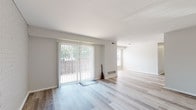 Located at 120 Elm St in Edgewater Park, New Jersey, this single-floor residence offers a clean, updated interior with a bright and neutral design palette. The open living and dining areas are finished with light-toned wood-style flooring that extends throughout the main spaces, creating a cohesive and airy feel. Large sliding glass doors dressed with vertical blinds flood the living area with natural light and provide direct access to an outdoor space, while additional windows offer views of surrounding greenery.

The kitchen is a standout feature, showcasing high-gloss white cabinetry, marble-look countertops, a stainless steel gas range with a wall-mounted range hood, and a single basin sink — combining modern style with functional design. The light wood-style flooring continues seamlessly into the kitchen, maintaining visual flow throughout.

The bedroom is carpeted in soft grey, providing a comfortable and quiet retreat, and is well-lit by a large window with outdoor views. The bathroom is clean and functional, featuring a full soaking tub with a shower, grab bars for added accessibility, and a crisp all-white finish. The overall ambiance of this residence is fresh, minimalist, and move-in ready.