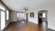 Located at 11289 E Hamilton Crest Blvd in Fishers, Indiana, this two-story home offers a well-designed layout with thoughtful architectural details throughout. The main level showcases a spacious, open-concept living area finished with rich, dark hardwood flooring that extends seamlessly throughout the space. Natural light pours in through a multi-pane window arrangement, illuminating the room and highlighting the warm tones of the floors. A ceiling fan with integrated lighting adds both function and a classic touch to the living area. Elegant arched doorways frame the transitions between rooms, lending a refined architectural character to the home. The kitchen is a standout feature, boasting dark cabinetry, granite countertops, and pendant lighting above a raised breakfast bar — ideal for casual dining or entertaining. Stainless steel appliances, including a refrigerator, are visible, along with additional cabinetry providing generous storage. A built-in nook area adjacent to the kitchen adds further utility and design interest. The neutral wall tones and white ceilings create a clean, versatile backdrop throughout the main level. With two floors of living space, this Fishers home combines practical layout with quality finishes in a well-established Indiana community.