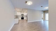 Located at 2 Plainview Lane in Newburgh, NY, this thoughtfully designed single-floor unit offers a comfortable and modern living experience. Light-toned hardwood-style flooring flows seamlessly throughout, creating a cohesive and bright aesthetic across every room.

The open-concept kitchen and living area forms the heart of the home. The kitchen is well-appointed with crisp white shaker cabinets, gray countertops, a subway tile backsplash, and a full suite of stainless steel appliances including a range, microwave, and dishwasher, all illuminated by recessed lighting. The adjacent combined dining and living room is spacious and airy, with a sliding glass door that opens to a private balcony, inviting natural light and outdoor views.

The bedroom is generously sized and features a large window that frames outdoor greenery, offering a calm and restful atmosphere. A well-organized walk-in closet with wire shelving provides ample storage. The den offers additional flexible living space, ideal for a home office or secondary lounge.

The bathroom is finished with a gray shaker-style vanity, white countertop, a lighted mirror, and a tub-shower combination with tiled surround. A dedicated laundry area and additional closet storage round out the practical features of this well-planned home.