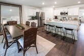 This thoughtfully designed single-story home offers a cohesive floor plan that connects living, dining, and sleeping areas with ease. A welcoming hallway sets the tone upon entry, lined with rich dark hardwood flooring that continues throughout the main living spaces and accented by crisp white walls that lend a bright, airy feel.

The living room features vaulted ceilings with a ceiling fan and light fixture, creating a sense of openness. The kitchen is outfitted with white shaker cabinetry, granite countertops, and stainless steel appliances, including a range and over-the-range microwave. The dining area adjoins the kitchen and opens to the outdoors through a set of glass French doors, allowing natural light to fill the space.

The primary bedroom is generously sized with a ceiling fan, natural light from large windows, and direct access to an en suite bathroom. The primary bath includes a dual-sink vanity with white cabinetry and quartz countertops, a soaking tub, a separate glass-enclosed shower, and tile flooring. A secondary bedroom provides a comfortable and versatile space. A full secondary bathroom features a tub-shower combination and tile flooring.

A dedicated laundry room includes a full-size washer and dryer with overhead shelving for added storage, completing this well-rounded home.
