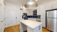 Located at 2125 E Apache Blvd in Tempe, Arizona, this well-designed 2-bedroom, 2-bathroom residence offers a thoughtful single-floor layout with a clean, contemporary aesthetic. The open-concept kitchen serves as the heart of the home, showcasing striking cobalt blue subway tile backsplash, crisp white cabinetry with modern hardware, stainless steel appliances including a refrigerator, range, microwave, and dishwasher, and a central island illuminated by bold pendant lighting. Warm-toned wood-look flooring flows seamlessly throughout the entire unit, lending a cohesive and inviting feel. The living area is open and airy, benefiting from recessed lighting and a clean white palette. The primary bedroom is generously proportioned and connects to a dedicated closet with built-in shelving, offering practical storage solutions. The second bedroom features a window with natural light and ample space. Both bathrooms are finished with wood-look flooring and white fixtures, with one bathroom featuring a full soaking tub and subway-tiled shower surround with brushed nickel hardware. The overall design is modern and minimal, with consistent finishes that create a polished, move-in-ready environment suited for Tempe living.