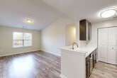 Located at 20268 River Ridge Terr, Unit 300 in Ashburn, VA, this two-bedroom, one-bathroom unit offers a thoughtfully designed single-floor layout. The open-concept living, dining, and kitchen area serves as the heart of the home, featuring vaulted ceilings that lend a sense of spaciousness. The kitchen is appointed with dark espresso cabinetry, a white countertop peninsula with an undermount sink, a tile backsplash, and stainless steel appliances, including a range and refrigerator. Wood-style plank flooring runs throughout the main living areas, while a pendant chandelier adds a decorative accent above the dining space. Natural light filters in through windows overlooking greenery, enhancing the bright, neutral color palette throughout. The primary bedroom is a comfortable size with wood-style flooring and a window with outdoor views, while the second bedroom features plush carpeting, a closet, and natural light. Additional closets are distributed throughout the unit for ample storage. The full bathroom includes a tub-shower combination with tile surround. An in-unit laundry area adds everyday convenience, completing this well-equipped and efficiently organized home.