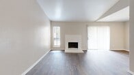 This one-bedroom, one-bathroom unit at 14403 Ella Blvd in Houston, TX offers a thoughtfully arranged single-floor layout. The living room is a standout space, featuring soaring vaulted ceilings that create an open, airy feel. A white brick fireplace serves as the room's focal point, flanked by windows with blinds and a sliding glass door that brings in natural light. Dark hardwood-style flooring runs throughout the living area, adding warmth and contrast to the neutral walls.

The kitchen is positioned adjacent to the living area and features gray cabinetry, providing functional storage and a clean aesthetic. A hallway connects the main living spaces to the private bedroom, which is finished with plush carpeting, a ceiling fan, and a window overlooking the surrounding neighborhood. The bedroom accesses a dedicated walk-in closet equipped with dual wire shelving systems and carpeted flooring, offering practical storage capacity.

The bathroom includes a full tub-shower combination with white tile surround, a toilet, and a granite-style countertop vanity. Brushed nickel hardware and a grab bar complete the space. Neutral tones and consistent finishes throughout give the unit a cohesive, well-maintained appearance.