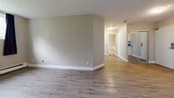 Located at 229 Amherst Drive in Amherstview, Ontario, this 2-bedroom, 1-bathroom unit offers a practical and modern layout across a single floor. Light-toned laminate flooring runs throughout the entire space, creating a cohesive and easy-to-maintain finish. The combined kitchen and living area forms the heart of the unit, with the kitchen featuring white shaker-style cabinetry, mosaic tile backsplash, white quartz-style countertops, and a full suite of stainless steel appliances including a refrigerator, electric range, over-the-range microwave, and dishwasher. The open living area flows seamlessly from the kitchen, with a hallway connecting to the bedrooms and bathroom. The primary bedroom is a comfortable size, benefiting from a wide window that brings in natural light and views of the surrounding landscape, complemented by baseboard heating. The second bedroom is similarly bright, with its own window and clean neutral walls. The bathroom is finished with a full soaking tub surrounded by large-format marble-look tile, offering a clean and refined aesthetic. A dedicated closet provides additional storage. The unit presents a clean, move-in ready environment with a neutral palette throughout.