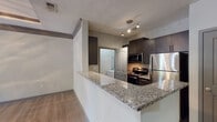 Located in the Country Walk community in Snellville, Georgia, this single-story 1-bedroom, 1-bathroom residence offers a thoughtfully designed layout with modern finishes throughout. The living area serves as the centerpiece of the home, showcasing a distinctive tray ceiling with crown molding detail and a ceiling fan, creating an elevated sense of space. Wood-style flooring flows through the main living areas, adding warmth and cohesion, while French doors invite natural light and provide access to the outdoors.

The kitchen is designed for both function and style, featuring granite countertops, dark cabinetry, and a full suite of stainless steel appliances including a refrigerator, range, and microwave. A peninsula counter with an undermount sink opens toward the living area, creating a convenient and connected layout. Track lighting illuminates the kitchen workspace effectively.

The bedroom is a comfortable retreat with plush carpeting, a sizable window overlooking greenery, and a textured ceiling. The bathroom is clean and modern, equipped with a granite-topped vanity, dark cabinetry with brushed nickel hardware, a large mirror, and light wood-style flooring. The overall ambiance of the unit is contemporary and move-in ready, reflecting a practical yet polished living environment.