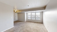 Located at 5179 Dempster Dr in Columbus, Ohio, this single-floor 2-bedroom, 1-bathroom residence offers a practical and comfortable layout. The open living area is generously sized, featuring wall-to-wall carpet, neutral gray walls, and a textured ceiling with a ceiling fan. A wide bank of windows along one wall floods the space with natural light and offers views of the surrounding neighborhood, creating a bright and airy atmosphere.

The galley-style kitchen is a standout feature, appointed with dark gray shaker-style cabinetry, crisp white countertops, a stainless steel sink, and black appliances including a range and refrigerator. Light tile flooring ties the kitchen together with a clean, modern aesthetic.

The spacious primary bedroom offers generous room to accommodate a variety of furniture arrangements, with soft carpeting and large windows that continue the home's emphasis on natural light. The second bedroom is equally well-proportioned, with carpeted floors and a bright window with blinds. Two closets provide practical storage throughout the home.

The full bathroom features a white tub-shower combination, a dark-cabineted vanity with a light countertop, and tile flooring, maintaining the clean and updated feel found throughout the residence.