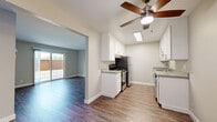 Located in Castro Valley, CA (94546), this single-floor residence offers a clean, contemporary layout with thoughtful finishes throughout. The kitchen is a standout feature, designed in a galley style with crisp white cabinetry, gray countertops, stainless steel appliances including a gas range and refrigerator, and a skylight that fills the space with natural light. A ceiling fan overhead adds both style and functionality. Light wood-tone flooring runs through the kitchen and transitions seamlessly into the open living area, which features warm neutral walls, a welcoming entry with two white doors, and ample room for comfortable furnishings. Sliding glass doors in the adjacent area bring in additional natural light and provide outdoor access. The bedrooms are finished with plush carpeting and neutral tones, offering a quiet and comfortable retreat. One bedroom features a large window with vertical blinds, inviting natural light and neighborhood views. The bathroom is well-appointed with a full tub-and-shower combination, white tile surround, a single-basin vanity with gray countertop, a mirrored medicine cabinet, and wood-look flooring that ties the space together. The overall aesthetic is clean, modern, and move-in ready.