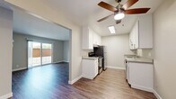 Located in Castro Valley, CA (94546), this single-floor residence offers a clean, contemporary layout with thoughtful finishes throughout. The kitchen is a standout feature, designed in a galley style with crisp white cabinetry, gray countertops, stainless steel appliances including a gas range and refrigerator, and a skylight that fills the space with natural light. A ceiling fan overhead adds both style and functionality. Light wood-tone flooring runs through the kitchen and transitions seamlessly into the open living area, which features warm neutral walls, a welcoming entry with two white doors, and ample room for comfortable furnishings. Sliding glass doors in the adjacent area bring in additional natural light and provide outdoor access. The bedrooms are finished with plush carpeting and neutral tones, offering a quiet and comfortable retreat. One bedroom features a large window with vertical blinds, inviting natural light and neighborhood views. The bathroom is well-appointed with a full tub-and-shower combination, white tile surround, a single-basin vanity with gray countertop, a mirrored medicine cabinet, and wood-look flooring that ties the space together. The overall aesthetic is clean, modern, and move-in ready.