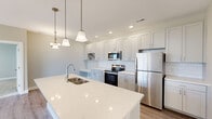 Located at 1330 Meeting St in Evansville, Indiana, this well-appointed single-floor home offers two bedrooms, two full bathrooms, dedicated closets, a laundry room, and a thoughtfully designed kitchen — all within a comfortable and cohesive layout. The kitchen serves as the heart of the home, showcasing white shaker cabinetry, a classic subway tile backsplash, gleaming quartz countertops, a large center island with an undermount sink, and a full suite of stainless steel appliances. Elegant pendant lighting adds warmth overhead. An adjacent built-in desk and cabinetry area provides a functional workspace or dining nook. Both bedrooms are finished with plush carpeting and ceiling fans, while the generously sized primary bedroom features sliding glass door access to a private balcony. A spacious walk-in closet with wire shelving serves the primary suite. The bathrooms are finished with wood-look flooring, white vanities, and a standout glass-enclosed shower adorned with marble-style tile surround. An in-unit laundry room houses a full-size washer and dryer. Throughout the home, neutral tones, recessed lighting, and clean architectural lines create a bright, modern, and move-in-ready living environment.