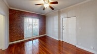 This single-floor, 2-bedroom, 1-bathroom residence offers a well-organized layout that maximizes its compact footprint. Rich hardwood flooring runs throughout all rooms, providing a warm, cohesive aesthetic that ties the space together. Crown molding is present throughout, adding a refined architectural detail to each room.

The living area is a notable highlight, featuring an exposed brick accent wall, a ceiling fan with light fixture, and a window with blinds that admits natural light. The primary bedroom is the most spacious room in the unit, with a ceiling fan, two closets—one of which is a walk-in—and a connecting hallway. The second bedroom also features crown molding, a closet, and windows that allow natural light to enter.

The kitchen is efficiently designed with rich dark-stained wood cabinetry, light countertops, a stainless steel undermount sink, and a stainless steel gas range with overhead ventilation. The bathroom features a tub/shower combination with classic white subway tile and a decorative mosaic border accent in warm earth tones. Two hallways connect the rooms, and a dedicated closet provides additional storage within the unit.