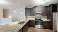 Located in Marietta, GA, this two-story, two-bedroom, two-bathroom home offers a well-designed layout across two levels. The garage entry level provides convenient parking and direct interior access via a staircase leading to the main living floor above. The main level hosts a combined kitchen and living area, where the kitchen stands out with rich dark cabinetry, granite countertops, a mosaic tile backsplash, stainless steel appliances, and elegant pendant lighting over a peninsula that opens seamlessly to the living space. Hardwood-style flooring flows throughout the main living areas, lending a warm, cohesive feel. Both bedrooms are carpeted and generously sized, with the primary bedroom featuring natural light from a large window and a ceiling fan. Each bedroom is supported by a dedicated closet with wire shelving systems. The two bathrooms are clean and functional, featuring tiled tub-shower combinations with brushed nickel fixtures. A dedicated laundry room with shelving adds everyday practicality. A bright hallway with crown molding connects the upper-level rooms, completing a comfortable and functional home well-suited for a variety of lifestyles.