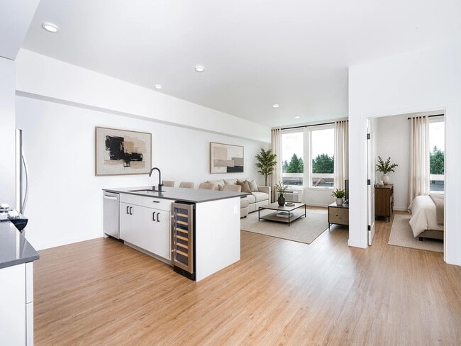 Open-concept living with a spacious kitchen island, integrated wine storage, and seamless flow between dining, lounge, and private bedroom areas. - Modera Bridle Trails