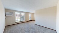 Located at 1290 Sanlor Ave in West Milton, Ohio, Unit 2 is a single-floor residence thoughtfully laid out for functional living. The generously sized living room is a standout feature, bathed in natural light from multiple large windows that offer views of the surrounding neighborhood. Soft carpet flooring, neutral beige walls, and rich dark baseboards create a warm, understated aesthetic throughout the main living areas. A wall-mounted air conditioning unit and baseboard heating ensure year-round comfort.

The kitchen is positioned just off the living area and features warm wood cabinetry, granite-toned countertops, a white electric range with overhead ventilation, and light hardwood-style flooring — providing a practical and efficient cooking space.

The bedroom is a well-proportioned room with carpeted flooring, a window for natural light, and a full-width sliding closet for ample storage. A separate door leads to additional access points within the unit.

The bathroom is clean and straightforward, featuring a single-sink vanity with wood cabinetry, a full tub/shower combo with a white surround, and light wood-style flooring. The entry area includes a windowed wall and direct exterior door access, completing this well-organized and move-in-ready residence.