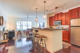 This single-story space in Opelika, Alabama offers a thoughtfully designed interior that blends functional living with an eclectic, welcoming aesthetic. Throughout the main living areas and kitchen, rich polished concrete floors in a deep mahogany tone create a striking visual foundation. The living room features classic beadboard wainscoting along the lower walls, adding texture and character, while large windows fitted with horizontal blinds allow ample natural light and views of the surrounding greenery.

The kitchen is well-appointed with warm cherry wood cabinetry, dark granite countertops, and a full suite of stainless steel appliances, including a range, microwave, and refrigerator. A breakfast bar with industrial-style seating provides a casual dining option, complemented by a dedicated dining nook with a tray ceiling and its own seating area nearby.

The bedrooms offer a softer atmosphere, with plush carpeting underfoot and windows that invite natural light. Each room provides a comfortable, restful environment. The bathrooms maintain the concrete flooring aesthetic and include combination tub-shower units, with one bathroom featuring rich cherry vanity cabinetry paired with granite countertops and a large mirror, reflecting the cohesive design language found throughout the space.