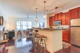 This single-story space in Opelika, Alabama offers a thoughtfully designed interior that blends functional living with an eclectic, welcoming aesthetic. Throughout the main living areas and kitchen, rich polished concrete floors in a deep mahogany tone create a striking visual foundation. The living room features classic beadboard wainscoting along the lower walls, adding texture and character, while large windows fitted with horizontal blinds allow ample natural light and views of the surrounding greenery.

The kitchen is well-appointed with warm cherry wood cabinetry, dark granite countertops, and a full suite of stainless steel appliances, including a range, microwave, and refrigerator. A breakfast bar with industrial-style seating provides a casual dining option, complemented by a dedicated dining nook with a tray ceiling and its own seating area nearby.

The bedrooms offer a softer atmosphere, with plush carpeting underfoot and windows that invite natural light. Each room provides a comfortable, restful environment. The bathrooms maintain the concrete flooring aesthetic and include combination tub-shower units, with one bathroom featuring rich cherry vanity cabinetry paired with granite countertops and a large mirror, reflecting the cohesive design language found throughout the space.