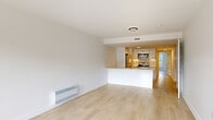 Located at 5150 Earnscliffe in Montréal, unit 305 presents a well-designed, single-floor residence characterized by a clean, modern aesthetic throughout. Light wood-tone flooring runs continuously across the entire unit, creating a cohesive and airy feel from room to room.

The open-concept living and dining area is generously proportioned, with large windows and a door providing direct access to a private balcony overlooking surrounding greenery and the neighbourhood streetscape. Baseboard heating units are positioned beneath the windows, ensuring comfort throughout the seasons.

The kitchen is thoughtfully designed with white flat-front cabinetry extending to the ceiling, light stone countertops, and a full suite of stainless steel appliances, including a refrigerator, electric range, built-in microwave, and dishwasher. A peninsula with an integrated sink separates the kitchen from the living space, offering both functionality and an open sightline.

Additional rooms include well-proportioned bedroom spaces with access to a dedicated storage area outfitted with adjustable wire shelving systems for organized storage. An in-unit washer is also visible in the floor plan, adding everyday convenience. The overall palette of white walls, light floors, and neutral finishes gives the unit a bright, contemporary character throughout.
