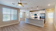 Located at 625 Creekside Way in New Braunfels, Texas, this single-story residence offers a clean, modern aesthetic with thoughtfully designed living spaces. The open-concept living and kitchen area is anchored by light wood-tone flooring that flows seamlessly throughout, creating a bright and cohesive atmosphere. Large windows with classic blinds invite ample natural light, while a ceiling fan adds both style and function to the living area.

The kitchen is a standout feature, showcasing white shaker-style cabinetry, a subway tile backsplash, granite countertops, and a spacious center island with pendant lighting overhead. Stainless steel appliances, including a refrigerator with ice dispenser, microwave, and range, complete the contemporary look.

The bedrooms are carpeted for comfort and include walk-in closets with built-in shelving. The bathrooms feature granite-topped white vanities and wood-look flooring, with one bathroom offering a soaking tub with gold-tone fixtures and a bright window above. An additional bathroom includes vanity storage and direct access to a walk-in closet. A dedicated laundry area with a full-size washer and utility space adds everyday convenience to this well-appointed home.