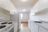 Located at 275 Wentworth St W in Oshawa, Ontario, this 2-bedroom, 2-bathroom unit offers a well-organized single-floor layout designed for comfortable everyday living. The space features a mix of classic parquet hardwood flooring in the living, dining, and primary bedroom areas, while the secondary bedroom and closet showcase light-toned laminate flooring. Baseboard heating is present throughout, ensuring consistent warmth across all rooms.

The galley-style kitchen is outfitted with white cabinetry, a double sink, and white appliances including a stove and refrigerator. Light tile flooring and a window bring natural light into the cooking area, which opens into the combined dining and living room — a generous, bright space with warm parquet flooring.

The spacious primary bedroom benefits from large windows that frame views of the surrounding Oshawa cityscape, while a dedicated closet with built-in shelving on both sides provides ample storage. The second bedroom is well-sized with laminate flooring and a clean, neutral finish. Both bathrooms are functional and simply appointed, with one featuring a full bathtub and shower combination with white surround panels. The overall aesthetic is clean and minimal, with white walls throughout creating a bright, versatile canvas.