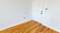 Located at 2110 Pickens St in Columbia, SC, this one-bedroom, one-bathroom apartment offers a thoughtfully designed layout across a single floor. Warm-toned hardwood flooring flows throughout the living spaces, complementing the crisp white walls and creating a bright, welcoming ambiance. The living room is generously proportioned, featuring tall ceilings, abundant natural light, and a paneled entry door with a transom window above. The bedroom is a comfortable size, with a natural light from a classic double-hung window and two closets offering ample storage. The kitchen is a standout feature, outfitted with rich dark cabinetry, granite countertops, a white subway tile backsplash, mosaic tile flooring, and a full suite of stainless steel appliances including a refrigerator, range, microwave, and dishwasher. The bathroom continues the refined aesthetic with large-format tile flooring, a dark vanity with granite countertop, a wide mirror with overhead lighting, a tub-shower combination, and built-in open shelving for convenient storage. A connecting hallway ties the rooms together efficiently, completing this well-appointed urban residence.