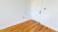 Located at 2110 Pickens St in Columbia, SC, this one-bedroom, one-bathroom apartment offers a thoughtfully designed layout across a single floor. Warm-toned hardwood flooring flows throughout the living spaces, complementing the crisp white walls and creating a bright, welcoming ambiance. The living room is generously proportioned, featuring tall ceilings, abundant natural light, and a paneled entry door with a transom window above. The bedroom is a comfortable size, with a natural light from a classic double-hung window and two closets offering ample storage. The kitchen is a standout feature, outfitted with rich dark cabinetry, granite countertops, a white subway tile backsplash, mosaic tile flooring, and a full suite of stainless steel appliances including a refrigerator, range, microwave, and dishwasher. The bathroom continues the refined aesthetic with large-format tile flooring, a dark vanity with granite countertop, a wide mirror with overhead lighting, a tub-shower combination, and built-in open shelving for convenient storage. A connecting hallway ties the rooms together efficiently, completing this well-appointed urban residence.
