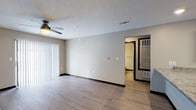 This single-floor unit is designed with a practical, open-concept layout that connects the living and kitchen areas seamlessly. The kitchen serves as a central hub, featuring a large peninsula with granite-style countertops, dark espresso cabinetry, and a full suite of stainless steel appliances including a refrigerator, range, microwave, and dishwasher. Recessed lighting and a dedicated under-cabinet light illuminate the workspace effectively. Wood-look laminate flooring extends throughout the main living areas, providing a cohesive and easy-to-maintain surface. The living room is equipped with a ceiling fan and offers access to an outdoor area through a sliding glass door fitted with vertical blinds.

The bedrooms are carpeted for comfort, each featuring windows with blinds that allow natural light and ceiling fans or flush-mount lighting. The unit includes two full bathrooms, both finished with granite-topped dark vanities, tub-shower combinations, and wood-look flooring. Neutral warm-gray tones are carried consistently throughout all rooms, contributing to a clean, modern aesthetic. Dark base trim provides a defined contrast against the lighter walls and flooring across the entire unit.