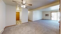 Located at Palmer Drive in Janesville, Wisconsin, this 2-bedroom, 2-bathroom single-floor residence offers a functional and comfortable layout. The open living area features soft carpeting, warm neutral walls, and a ceiling fan with light fixture, creating a welcoming atmosphere. A wall-mounted AC unit and baseboard heating ensure year-round comfort, while a sliding glass door fills the space with natural light and provides access to an outdoor area. The layout connects the living space to a hallway leading to all other rooms. The primary bedroom is generously sized, featuring carpet flooring, a large window, and two sliding-door closets framed in warm oak wood trim, offering ample storage. The second bedroom also includes carpet flooring and its own sliding-door closet. Both bathrooms feature wood-toned cabinetry with wide vanity countertops, large mirrors with overhead lighting, and durable vinyl plank flooring in contrasting styles — one with a tub/shower combination and one as a three-quarter bath. An in-unit laundry area is accessible from the hallway. Warm wood-toned doors and oak trim accents throughout lend a consistent, classic character to the home. The tiled entryway provides a practical transition point into the main living areas.