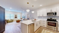 Located at 21 Raymond Ave in Poughkeepsie, NY, this thoughtfully designed single-floor residence offers a seamless blend of modern aesthetics and functional living. The open-concept kitchen is a standout feature, outfitted with crisp white shaker cabinetry, black hardware accents, a subway tile backsplash, stainless steel appliances, and a central island with a stainless sink and pendant lighting overhead. Light hardwood flooring flows throughout, unifying the space with warmth and continuity.

The kitchen transitions naturally into a bright and welcoming living area, where multiple windows invite abundant natural light and create an airy, relaxed atmosphere. The bathrooms are elegantly appointed, featuring hexagonal penny tile flooring, white shaker vanities with black fixtures, and dual-mirror setups that enhance both style and practicality. A dedicated home office provides a quiet, well-lit retreat with an outdoor-facing window. The bedroom area is complemented by a spacious walk-in closet with built-in shelving and double hanging rods, offering generous storage. Throughout the residence, a neutral color palette, recessed lighting, and clean architectural lines create a cohesive, contemporary ambiance suited for comfortable everyday living.