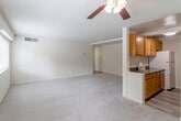 This single-floor residence offers a practical and comfortable layout highlighted by neutral tones and carpeted flooring throughout the living and sleeping areas. The open living room is generously sized, featuring a ceiling fan with light fixture, smooth walls, and a seamless connection to the kitchen via a half-wall partition. Natural light filters in through windows, creating a bright and inviting atmosphere.

The galley-style kitchen is well-appointed with warm wood cabinetry lining both walls, dark granite-style countertops, and hardwood-style flooring. It includes a full suite of white appliances — a gas range, refrigerator, and over-the-range microwave — alongside a sink and ample upper and lower cabinet storage.

The bedrooms are carpeted and offer a calm, neutral environment. One bedroom features dual bi-fold closets with built-in shelving, providing substantial storage, as well as a window with outdoor views of surrounding greenery.

The bathroom is clean and functional, outfitted with a tiled tub-and-shower combination, toilet, vanity sink, and overhead cabinetry for additional storage. Throughout the unit, the consistent neutral color palette and straightforward layout contribute to a cohesive and move-in-ready living environment.