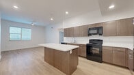 This single-story, 3-bedroom, 2-bathroom home in Austin, TX offers a clean and modern design with consistent light wood flooring and crisp white walls throughout. The open-concept kitchen serves as the heart of the home, featuring warm medium-tone wood cabinetry extending to the ceiling, white countertops, a central island with bar overhang, and a full suite of black appliances including a gas range, dishwasher, microwave, and refrigerator. Recessed lighting illuminates the space, which flows seamlessly into the adjacent living area. The three bedrooms are bright and airy, each finished with the same light wood flooring and neutral walls. Two of the bedrooms feature ceiling fans and windows with blinds that allow natural light to filter in. The primary bedroom offers a comfortable footprint, while the additional bedrooms provide versatile spaces suitable for various needs. The two bathrooms are finished with tile flooring. One bathroom includes a soaking tub with a white subway-tiled surround, while the second features a walk-in shower. Both bathrooms include wood-toned cabinetry. The overall aesthetic is modern, clean, and move-in ready, with a neutral palette that offers a welcoming atmosphere.