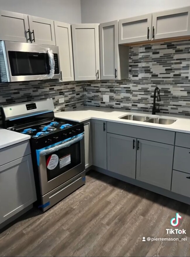 Beautiful modernized kitchen w/grey cabinets, black accents & a backsplash to bring it all together. - 5733 S Morgan St