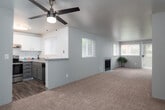 This single-floor residence offers a thoughtfully designed layout with comfortable, functional living spaces throughout. The open-concept living and dining area is a standout feature, showcasing plush wall-to-wall carpeting, soft neutral wall tones, and a ceiling fan overhead. Multiple windows allow natural light to fill the space, and a fireplace serves as a focal point at the far end of the room. Sliding glass doors lead to an outdoor area, further enhancing the sense of openness.

The kitchen is efficiently laid out with a convenient pass-through window connecting it to the living area. It features stainless steel appliances including an electric range, gray lower cabinetry, white upper cabinets, granite-style countertops, and a stainless steel sink — all finished with wood-look flooring for easy maintenance.

The residence includes two bathrooms: a full bath with a tub-shower combination, granite-style vanity countertop, and wood-look flooring, as well as a secondary bathroom with a walk-in shower. A dedicated in-unit laundry area accommodates a full-size washer and dryer with overhead shelving for additional storage. The bedroom area is generously sized with carpeting and a ceiling fan, completing this well-rounded and practical home.