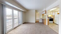 This single-floor unit in Ypsilanti, Michigan, offers a practical and comfortable layout encompassing one bedroom and one bathroom. The open living area is finished with wall-to-wall carpeting and neutral cream-toned walls, creating a clean, understated aesthetic. A defining feature of the living space is the sliding glass door that leads to a private balcony, allowing natural light to fill the room and providing outdoor views of the surrounding area.

The kitchen is efficiently designed in a U-shaped configuration, featuring oak-trimmed cabinetry with white panel fronts, laminate countertops, tile flooring, and white appliances including a refrigerator, electric range, and dishwasher. A pass-through connects the kitchen to the main living area, enhancing the open feel of the space.

The bedroom offers generous proportions with carpeted flooring, a large window admitting natural light, and ample wall space. The full bathroom includes mosaic tile flooring, a dark wood vanity with a marble-style countertop, a large mirror with overhead lighting, and a shower-tub combination.

A notable practical feature is the in-unit laundry area, which accommodates a full-sized washer and dryer, adding everyday convenience to this well-appointed Ypsilanti residence.