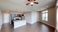 This single-floor residence offers a thoughtfully designed open-concept layout that seamlessly connects the kitchen and living areas. The kitchen is appointed with rich dark-wood cabinetry, granite countertops, stainless steel appliances including a gas range, microwave, and refrigerator, and a central island with an undermount sink. Pendant lighting and recessed fixtures illuminate the space, while wood-look flooring extends throughout the main living areas, adding warmth and continuity.

The living area is generously proportioned, featuring a ceiling fan, large windows that invite natural light, and direct sightlines to the kitchen — ideal for an open, connected feel. A dedicated living space with additional windows provides further flexibility.

The bedrooms are carpeted for comfort and each includes a ceiling fan. The primary bedroom is notably spacious, with tall windows, an en-suite bathroom, and access to a walk-in closet. Additional bedrooms are well-sized with easy access to hallway spaces. The bathrooms feature clean white tub and shower combinations with curved curtain rods and chrome fixtures, maintaining a consistent, functional aesthetic throughout the residence.