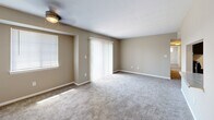 Located at 6525 Greenway Dr in Roanoke, Virginia, this single-floor residence offers a well-organized layout designed for comfortable everyday living. The kitchen is a functional galley-style space finished with white shaker cabinetry, marble-patterned countertops, a stainless steel sink, a gas range, and a dishwasher, all set above durable light wood flooring that adds warmth to the area. The living room is generously proportioned, featuring neutral-toned carpet, a ceiling fan, a side window for natural light, and a full-width sliding glass door flanked by vertical blinds that open to an outdoor balcony with views of surrounding greenery. Multiple bedrooms throughout the unit are carpeted and finished in soft neutral tones, each equipped with ceiling fans and windows fitted with horizontal blinds to allow natural light while maintaining privacy. One bedroom includes a wide louvered bi-fold closet, while the primary bedroom benefits from an en-suite bathroom and a dedicated walk-in closet, providing ample storage. The consistent use of neutral palettes, plush carpeting, and practical fixtures throughout creates a cohesive and move-in ready environment suited for a range of lifestyles.