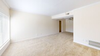 Located at 2619 Hydraulic Rd in Charlottesville, VA, this one-bedroom, one-bathroom unit offers a thoughtfully organized single-floor layout. The living room greets you at the entry with warm, neutral-toned carpet, crown molding, and a large window fitted with blinds that invites natural light and outdoor views. The space flows seamlessly into the dining area, creating a comfortable and connected common area. The kitchen is well-appointed with rich wood cabinetry, tile backsplash, laminate countertops, and a full suite of black appliances including a gas range, dishwasher, refrigerator, and over-the-range microwave. An electrical panel is conveniently accessible within the kitchen area. The bedroom offers a comfortable, carpeted retreat with a ceiling fan, a window overlooking the outdoors, and access to generous closet storage — four closets are distributed throughout the unit. The bathroom includes a full tub and shower combination with clean white tile surround and chrome fixtures. Completing the unit is a dedicated laundry area, adding everyday convenience. Neutral walls and plush carpet throughout create a clean, move-in-ready atmosphere.