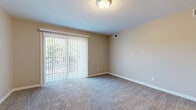 This well-appointed one-bedroom, one-bathroom unit at 3801 W 13th St N in Wichita, Kansas offers a practical and comfortable layout across a single floor. The living area is finished with neutral-toned carpet and features large sliding glass doors fitted with vertical blinds, allowing abundant natural light to fill the space and providing access to a private balcony overlooking lush greenery. The kitchen is equipped with white cabinetry, granite-style countertops, a stainless steel sink, and durable wood-look flooring, offering a clean and functional cooking space. The bedroom is a comfortable size, carpeted throughout, and features a ceiling fan with integrated lighting, a window with outdoor views, and access to closet storage. Two closets provide ample storage throughout the unit. A hallway connects the main living spaces to the bathroom, which includes a full bathtub and shower surround with built-in shelving. The unit's warm beige tones and white trim create a cohesive, neutral aesthetic throughout. With its efficient layout, natural light, and convenient location in Wichita, this unit is a practical and inviting living space.