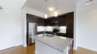 Located at 1005 West 5th Avenue in Columbus, Ohio's vibrant Grandview Heights neighborhood, this modern two-story residence showcases a thoughtfully designed interior with high-end finishes throughout. The open-concept kitchen serves as a standout feature, boasting rich dark espresso cabinetry that extends to the ceiling, creating a bold and sophisticated aesthetic. A large central island with granite countertops provides ample prep space and doubles as a casual dining area, anchored by elegant pendant lighting above. Stainless steel appliances, including a French door refrigerator, electric range, and built-in microwave, complete the chef-inspired space. White subway tile backsplash and crisp white walls contrast beautifully against the dark cabinetry, while warm hardwood-style flooring grounds the space with a welcoming feel. Generous ceiling heights amplify the sense of openness throughout. Spanning two floors, the layout offers a natural separation between living and private spaces, providing both functionality and comfort. The overall design palette is clean and contemporary, combining modern hardware details, durable surfaces, and a neutral color scheme that is both stylish and versatile.