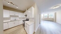 Located at 1920 Weston Rd in Toronto's Weston neighbourhood, this 2-bedroom, 1-bathroom unit offers a thoughtfully laid-out single-floor living space. Light-toned hardwood flooring runs throughout, lending a clean and cohesive feel to every room.

The kitchen is a standout feature, finished with crisp white shaker-style cabinetry, quartz countertops, a classic subway tile backsplash, and stainless steel appliances — combining both style and functionality. Ample upper and lower cabinet storage makes this kitchen as practical as it is attractive.

The spacious living area is bathed in natural light through large windows, with views of greenery outside. A baseboard heating system ensures year-round comfort. The two bedrooms are well-proportioned, with the primary bedroom offering a sliding-door closet for convenient storage. Neutral warm-beige walls throughout create a calm and inviting ambiance.

The bathroom is finished with large marble-style wall tiles surrounding the soaker tub and shower combination, complemented by clean white fixtures. A hallway connects the rooms efficiently, maximizing the use of the overall footprint. This unit presents a modern, move-in-ready interior with a light, airy aesthetic throughout.