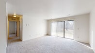 This single-floor residence offers a clean, functional layout designed for comfortable everyday living. The generously sized living area is finished with plush light-gray carpeting and crisp white walls, creating a bright and open atmosphere. A large sliding glass door fitted with vertical blinds fills the space with natural light while providing views of the surrounding greenery and direct access to the outdoors. A hallway connects the living area to the private quarters of the home.

The bedrooms are carpeted and well-proportioned, each featuring windows with vertical blinds that allow for natural light and outdoor views. One bedroom offers dual closets with warm wood-toned panel doors, providing ample storage. The full bathroom includes a tub-shower combination with white tile surround, a vanity with storage, and tile flooring in a warm earth tone.

The kitchen is equipped with a range, refrigerator, and cabinetry, offering a practical workspace. A dedicated utility area houses a full-size washer and dryer alongside a water heater, adding in-unit convenience. Throughout the space, the neutral color palette, consistent carpeting, and straightforward design create a cohesive and move-in-ready environment.