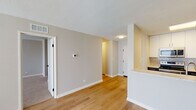 Located at 134 W St Charles Rd in Lombard, IL, this single-floor unit offers a thoughtfully updated interior with a clean, modern aesthetic throughout. The open-concept living and dining area is finished with warm-toned hardwood-style flooring and neutral walls, creating a bright and welcoming atmosphere. A large sliding glass door allows natural light to fill the space while providing an outdoor view.

The kitchen is positioned adjacent to the living area behind a half-wall peninsula, offering both separation and connectivity. It features dark cabinetry contrasted by white upper cabinets, quartz countertops, a classic subway tile backsplash, and stainless steel appliances including a Samsung range, over-the-range microwave, and refrigerator.

The bedrooms are carpeted and finished with neutral tones, each benefiting from windows that bring in natural light. The bathroom has been updated with light tile flooring, a dark vanity with a white countertop, a sliding glass shower enclosure over a tub, and modern black hardware accents. A textured ceiling is present throughout, and a smart thermostat is conveniently mounted in the main living area.