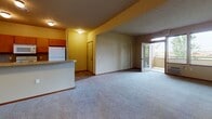 Located at 1090 West Betz Road in Cheney, Washington, this single-floor unit offers a practical and comfortable layout designed for everyday living. The open-concept living area is generously proportioned, featuring soft carpet flooring, textured ceilings, and baseboard heating throughout. Large windows allow natural light to fill the space while offering views of the surrounding greenery. A sliding glass door provides access to an outdoor balcony area, enhancing the connection between indoor and outdoor living.

The kitchen is efficiently arranged with warm wood cabinetry, a tile backsplash, laminate countertops, and a full suite of white appliances including a refrigerator, electric range, built-in microwave, and dishwasher. A double-basin sink and ample counter space make it well-suited for daily use. A peninsula counter separates the kitchen from the living area, creating a natural flow between the two spaces.

The bedrooms are carpeted and well-lit, each featuring windows that bring in outdoor views and natural light, along with baseboard heating for year-round comfort. The bathrooms are finished with tile flooring, warm-toned vanities with mirrors, and full tub and shower combinations. Rich wood-toned interior doors and trim add a cohesive, warm aesthetic throughout the unit.