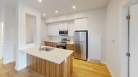 Located at 90 Starwood Dr, Unit 511 Hazel in Guelph, Ontario, this contemporary single-floor unit offers 100 square meters of thoughtfully designed living space across 3 bedrooms and 2 bathrooms. Light-toned hardwood flooring runs throughout, complementing the clean white walls and creating a bright, cohesive aesthetic.

The modern kitchen is a standout feature, equipped with stainless steel appliances including a refrigerator, electric range, and over-the-range microwave. Two-tone cabinetry pairs white upper cabinets with warm wood-grain lower cabinets, topped with white quartz countertops. A kitchen island with an integrated sink adds both workspace and visual appeal.

The primary bedroom measures 18 square meters and is served by a dedicated closet. The two additional bedrooms feature large windows that invite natural light and outdoor views. A second closet provides added storage for the unit.

Both bathrooms are finished with white subway tile surrounds in the tub-shower combinations, brushed nickel fixtures, white vanities with quartz countertops, and large mirrors. The open living area benefits from sliding door access and abundant natural light. The unit includes 2 closets, offering practical storage solutions throughout.
