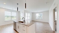 Located at 2551 Frontier Dr in Pittsburgh, PA, this well-appointed 2-bedroom, 2-bathroom residence offers a thoughtfully designed single-floor layout. The open-concept kitchen and living area serves as the heart of the home, featuring a large central island with a quartz countertop, undermount sink with a matte black faucet, and sleek pendant lighting. White shaker-style cabinetry, subway tile backsplash, and a full suite of stainless steel appliances — including a gas range, microwave, and refrigerator — complete the modern kitchen. Light hardwood-style flooring flows throughout the main living areas, enhancing the bright, airy feel aided by large windows that bring in natural light. The spacious living room offers a clean, open canvas with recessed lighting and direct sightlines to the kitchen. Both bedrooms are carpeted for comfort, each with windows offering exterior views. The primary bedroom includes a dedicated walk-in closet outfitted with wire shelving and hanging rods. Both bathrooms are finished with white subway tile tub surrounds, quartz vanity countertops, white cabinetry, and matte black fixtures, maintaining a consistent, contemporary aesthetic throughout the residence.
