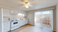 This well-organized single-story residence offers two bedrooms, one bathroom, and a thoughtfully laid-out floor plan that maximizes every square foot. The combined living, dining, and kitchen area serves as the heart of the home, featuring light wood-style flooring, a ceiling fan, and a sliding glass door that fills the space with natural light and provides outdoor access. The kitchen is equipped with white cabinetry offering generous upper and lower storage, white appliances including a range and dishwasher, a stainless steel sink, and light countertops — all finished with a clean, cohesive aesthetic.

The two bedrooms feature neutral carpet flooring, windows with blinds that bring in natural light, wall-mounted heating units, and textured ceilings. The primary bedroom includes a closet with built-in hanging rod. Three closets throughout the unit provide ample storage. The full bathroom features a tub-shower combination, a vanity with under-sink cabinetry, and light wood flooring, accented by brushed nickel hardware. A utility room and hallway complete the layout. The overall ambiance is bright, clean, and move-in ready, with a neutral palette throughout.