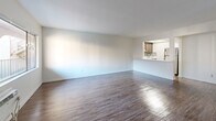 Located at 1801 W Garvey Ave in Alhambra, CA, this single-story one-bedroom, one-bathroom unit offers a functional and well-designed layout. The open-concept living and dining area is bright and spacious, featuring hardwood-style flooring that runs throughout the entire unit, clean white walls, and natural light streaming in through multiple windows. A pass-through counter connects the living area to the kitchen, which is equipped with wood cabinetry, a tile backsplash, and full-size appliances including a refrigerator. The bedroom is comfortably sized, offering a wide window with outdoor views of the surrounding neighborhood, a wall-mounted AC unit, and two closets — one featuring a rich dark wood finish and the other an open shelving design, providing ample storage. Built-in shelving in the living area adds additional organizational versatility. The bathroom is clean and efficiently designed, featuring a full tub-shower combination with brushed nickel fixtures, white cabinetry, and wood-style flooring that complements the rest of the unit. The overall aesthetic is clean, bright, and move-in ready, making this a practical and comfortable home in a convenient Alhambra location.