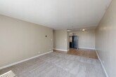 Located at 4185 E Florida Ave in Denver, CO, this one-bedroom, one-bathroom unit offers a practical and comfortable single-floor layout. The open-concept living and dining area is bright and inviting, featuring neutral beige walls, plush carpet, and large windows with vertical blinds that allow generous natural light to filter in. Wood-look flooring transitions seamlessly into the kitchen and hallway areas, adding warmth and visual continuity throughout.

The kitchen is efficiently designed with white cabinetry, granite-style countertops, a stainless steel refrigerator, and matching appliances, including a dishwasher and range. A ceiling-mounted light fixture keeps the space well-lit. The hallway connects the main living area to the bedroom and bathroom, featuring textured walls and a flush-mount ceiling light.

The bedroom is a well-sized, carpeted retreat with a window for natural light, a wall-mounted heating unit, and access to multiple closets, providing ample storage. The bathroom is clean and functional, appointed with brushed nickel fixtures, grab bars, and a classic white toilet. Overall, the unit presents a neutral, move-in-ready aesthetic suited for comfortable everyday living.